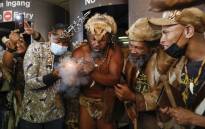 King Khoisan South Africa (second left) smokes outside the Pretoria Magistrates Court after his release following his arrest for planting marijuana on his campsite at the Union Buildings in Pretoria on 13 January 2022. Picture: Phill Magakoe/AFP