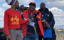 Numsa’s Enoch Manyoni addresses striking workers under three contractors (Newrak, Reagetswe, Triple M mining) that they’ve accused of exploiting workers by paying them a fraction of what their counterparts on permanent contracts get. Picture: Masechaba Sefularo/EWN.