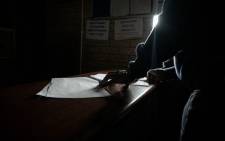 A police officer at the Lawley Community Service Station works by torchlight as the station has been without power for more than two years. Picture: Boikhutso Ntsoko/Eyewitness News