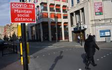 A pedestrian passes a social distancing sign as they cross an empty road in Liverpool, north-west England on 14 October 2020, as new local lockdown measures come in to force to help stem a second wave of the novel coronavirus. Picture: AFP