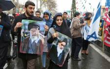 An Iranian man marches with a portrait of the country's Supreme Leader Ali Khamenei (L) alongside a woman holding up another of Islamic Revolution founder Ayatollah Ruhollah Khomeini (R) during a ceremony celebrating the 40th anniversary of Islamic Revolution in the capital Tehran on 11 February 2019. Picture: AFP
