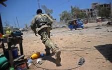 FILE: A Somali soldier runs for cover at the scene of two explosions set off near the ministries of public works and labour in Mogadishu on 23 March 2019. Picture: AFP