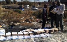 Police officers discovered social grant documents and police caps dumped in the veld in downtown joburg. Picture: Jacob Moshokoa/EWN