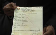 Home Affairs Director General holds up a sample of an SA unabridged birth certificate. Picture: Vumani Mkhize/EWN. 