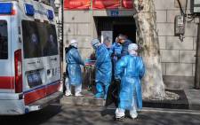 Medical staff in protective clothes are seen carrying a patient from an apartment suspected of having the virus in Wuhan, in Hubei province on 30 January 2020. Picture: AFP