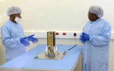 Minister of Science and Technology Mmamoloko Kubayi-Ngubane in the clean room with senior engineer Nyameko Royi and the ZACube-2. Picture: Supplied.