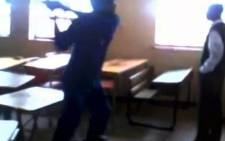 This screengrab from cellphone footage shows a man as he swings a broom at a Stanwest Combined School pupil, 15 May 2014. Picture: 'Standerton Advertiser' via YouTube.