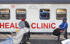 A nurse for Transnet-Phelophepa Healthcare Train points out the window as patients sit in a queue at the Dube Station in Soweto, on June 22, 2021. The Transnet-Phelophepa consists of custom-built trains that deliver primary healthcare to remote areas of South Africa. Picture: Phill Magakoe / AFP