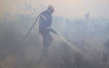FILE: A firefighter walks through a thick cloud of smoke while putting out a fire. Picture: Bertram Malgas/EWN