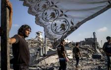Palestinians stand next to a makeshift shelter erected outside their destroyed house in the devastated neighbourhood of Shejaiya in Gaza City on 6 August, 2014. Picture: AFP.