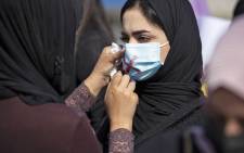 In this file photo taken on 8 March 2021, a demonstrator uses lipstick to cross out the mask of another protester as they attend a rally for International Women's Day in Iraq's southern city of Basra. Picture: AFP