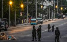 Soldiers keep watch as they block an empty street in Yangon on 10 March 2021, as security forces continue to crackdown on demonstrations by protesters against the military coup. Picture: AFP