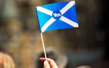 FILE: A pro-independence supporter holds a "Yes" flag as Scottish MP Jim Murphy addresses pro-union "Better Together" campaign supporters in Edinburgh on 8 September, 2014. Picture: AFP.