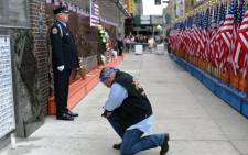 People pay their respects at the at the Fire Department of New York (FDNY) Memorial Wall Located at FDNY Engine and Ladder 10 on September 11, 2014 on the 13th anniversary of the September 11, 2001 attacks. AFP.