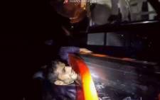 FILE: This image grabbed from a video taken on November 14, 2020 off the island of Lampedusa and handout on November 15, 2020 by the Italian Coast Guards (Guardia Costiera), shows a migrant clinging to a patrol boat of the Italian Coast Guards during a rescue operation after the capsizing of the migrants' boat. Picture: AFP.