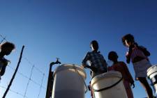 Youths fill their buckets with water from a tap after water supply was restored in Boitumelong Township in Bloemhof, North West on 29 May 2014. Picture: Sapa.