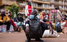 FILE: A traveller wears a face mask, as a preventive measure against the spread of the COVID-19 coronavirus, while he waits for an intercity bus at the Namirembe Bus Park in Kampala, Uganda, on 4 June 2020, the first day of re-opening public transport. Picture: AFP.