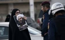 A Bahraini woman holds a poster of prominent Shiite Muslim cleric Nimr al-Nimr during clashes with riot police following a protest against the execution Nimr of by Saudi authorities, in the village of Daih, west of the capital Manama on 4 January, 2016. Picture: AFP.