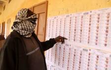 A voter wearing a scarf to cover his face checks the voter's roll at a polling station during the parliamentary elections in Gao, Mali, on 29 March 2020. Picture: AFP