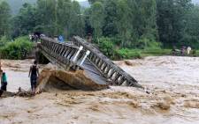 People look at the bridge which was washed away by the floodwaters in Thoubal District in Manipur state on 1 August, 2015. At least 21 people were killed in a landslide caused by heavy rains in Manipur’s Chandel district, said police. Picture: AFP.