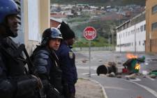 FILE: Police regroup behind a building before using rubber bullets to disperse angry protesters in Hangberg. Picture: EWN.