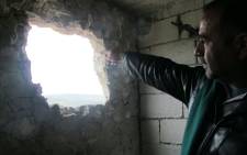 A Syrian man points to a hole in his wall after his town was attacked. Picture: Rahima Essop/EWN.
