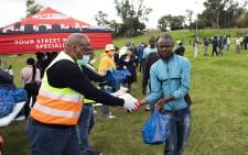 Johannesburg Environmental and Infrastructure MMC Mpho Moerane hands over maize to a waste picker during a food hamper drive at Innes Free Park in Sandton. Picture: Ahmed Kajee/EWN