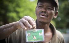 FILE: Patrick Amos, a gardener in Worcester, holds up his "dompas", a card issued by Sector 4 Saps in Worcester, with his name, photograph, and expiry date on it. Picture: Thomas Holder/EWN