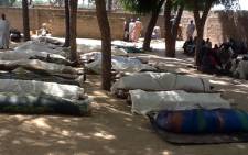 FILE: People stand next to dead bodies, which are laid out for burial, in the village of Konduga, in northeastern Nigeria, on 12 February, 2014 after a gruesome attack by Boko Haram Islamists killed 39 people. Picture: AFP.