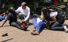  Injured people receive assistance from bypassers after masked gunmen stormed an upmarket Nairobi mall and sprayed gunfire on shoppers and staff on September 21, 2013 in Nairobi. Picture: AFP