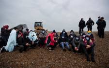 Migrants sit on the beach after being helped ashore from a RNLI (Royal National Lifeboat Institution) lifeboat at a beach in Dungeness, on the south-east coast of England, on 24 November 2021, after being rescued while crossing the English Channel. Picture: Ben STANSALL/AFP 