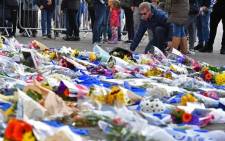 A man adds flowers to a growing pile of tributes outside Leicester City Football Club's King Power Stadium in Leicester, eastern England, on 28 October 2018 after a helicopter belonging to the club's Thai chairman Vichai Srivaddhanaprabha crashed outside the stadium the night before. Picture: AFP.