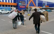 Evacuees who were driven in private buses and cars from Berdyansk and a few from Mariupol, carry their bags as they arrive at the registration center in Zaporizhzhia on 1 April 2022.