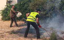 Residents try to extinguish a fire burning near houses at Vatera coastal resort on the eastern island of Lesbos on July 23, 2022. Residents were evacuated as the wilfire threatened properties. Picture:Manolis LAGOUTARIS / AFP.