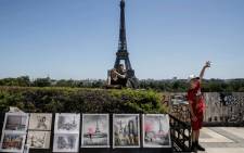 Tourists take a selfie under a blue sky with the Eiffel Tower behind and drawings in the front at the Trocadero Square, in Paris, on June 13, 2021. Picture: Sameer Al-Doumy / AFP