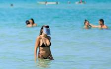 FILE: A woman wears a face shield as she wades in the ocean off South Beach on 10 June 2020 in Miami Beach, Florida. Picture: AFP