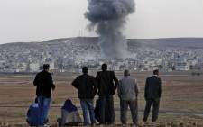 Local residents watch smoke from an explosion rising over the Syrian city of Kobani as they watch the apparent US-led coalition's airstrike against IS positions in the border region from a hillside on the Turkish side of the border near the Suruc district city of Sanliurfa, Turkey, on 22 October 2014. Picture: EPA.