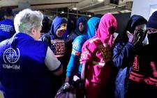 An International Organization for Migration (IOM) member stand next to Ivorian migrants returning from Libya to be repatriated in their country as they arrive at the airport of Abidjan on 20 November 2017. Picture: AFP.