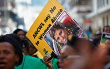 A woman holds a sign bearing the portrait of Anni Dewani as members of the ruling African National Congress Women's League protest against the abuse of women, outside the Cape Town High Court, where British murder accused, Shrien Dewani (unseen), is standing trial on 8 April, 2014. Picture: AFP.