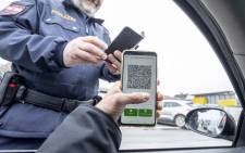 An Austrian police officer checks a driver's digital vaccination certificate on a smartphone during a traffic control in Graz, Austria, on 15 November 2021, during the ongoing coronavirus (Covid-19) pandemic. Picture: Erwin Scheriau/AFP