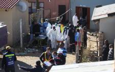 Forensic personnel carry a body out of a township pub in South Africa's southern city of East London on 26 June 2022 after 20 teenagers died. Picture: STR / AFP