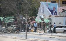 Security forces stand near a billboard depicting Somalian President Hassan Sheikh Mohamud, at the scene where two explosions occured in Mogadishu on 7 September 2013. Picture: AFP/ Mohamed Abdiwaha