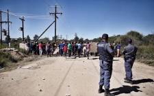 Police watch as residents continue to call for the removal of North West Premier Supra Mahumapelo on 20 April 2018. Picture: Ihsaan Haffejee/EWN