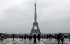 People walk on the Trocadero square in central Paris on 15 March, 2014, with the Eiffel tower in the background seen through a haze of pollution. Picture: AFP.
