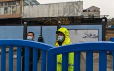 Guards stand at an entrance as members of the WHO team, investigating the origins of the coronavirus, arrive at the closed Huanan Seafood wholesale market in Wuhan on January 31, 2021. Picture: Hector Retamal/AFP. 