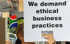 A woman holds a poster during a protest against McKinsey over 'irregular payments' involving Eskom and Trillian on 5 October 2017. Picture: Supplied.