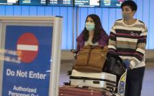 FILE: Passengers wear protective masks to protect against the spread of the Coronavirus as they arrive at the Los Angeles International Airport, California, on 22 January 2020. Picture: AFP