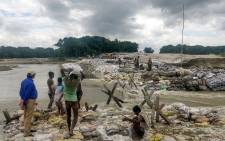 Locals gather concrete fragments and heavy bags wrapped in nets to build a dam as floodwaters flow from the north into the state of Indian eastern state of Bihar near Muzaffarpur on 13 July 2019. Picture: AFP