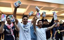 First customers display their iPhone X sets at an Apple showroom in Sydney on 3 November, 2017. Apple iPhone X went for sale in Australia with long queues outside the Apple stores. Picture: AFP.