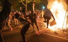FILE: Protesters jump on a street sign near a burning barricade during a demonstration against the death of George Floyd near the White House on 31 May 2020 in Washington, DC. Picture: AFP